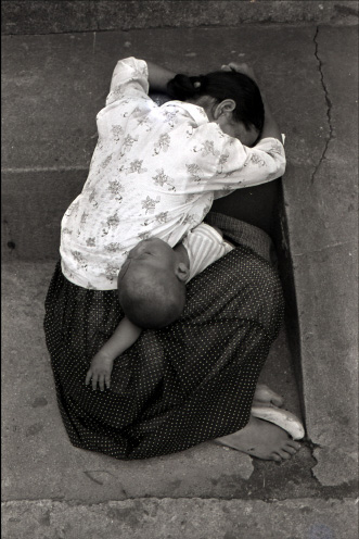 아이를 무릎 위에 재우고 바닥에 엎드려 누워있는 여자